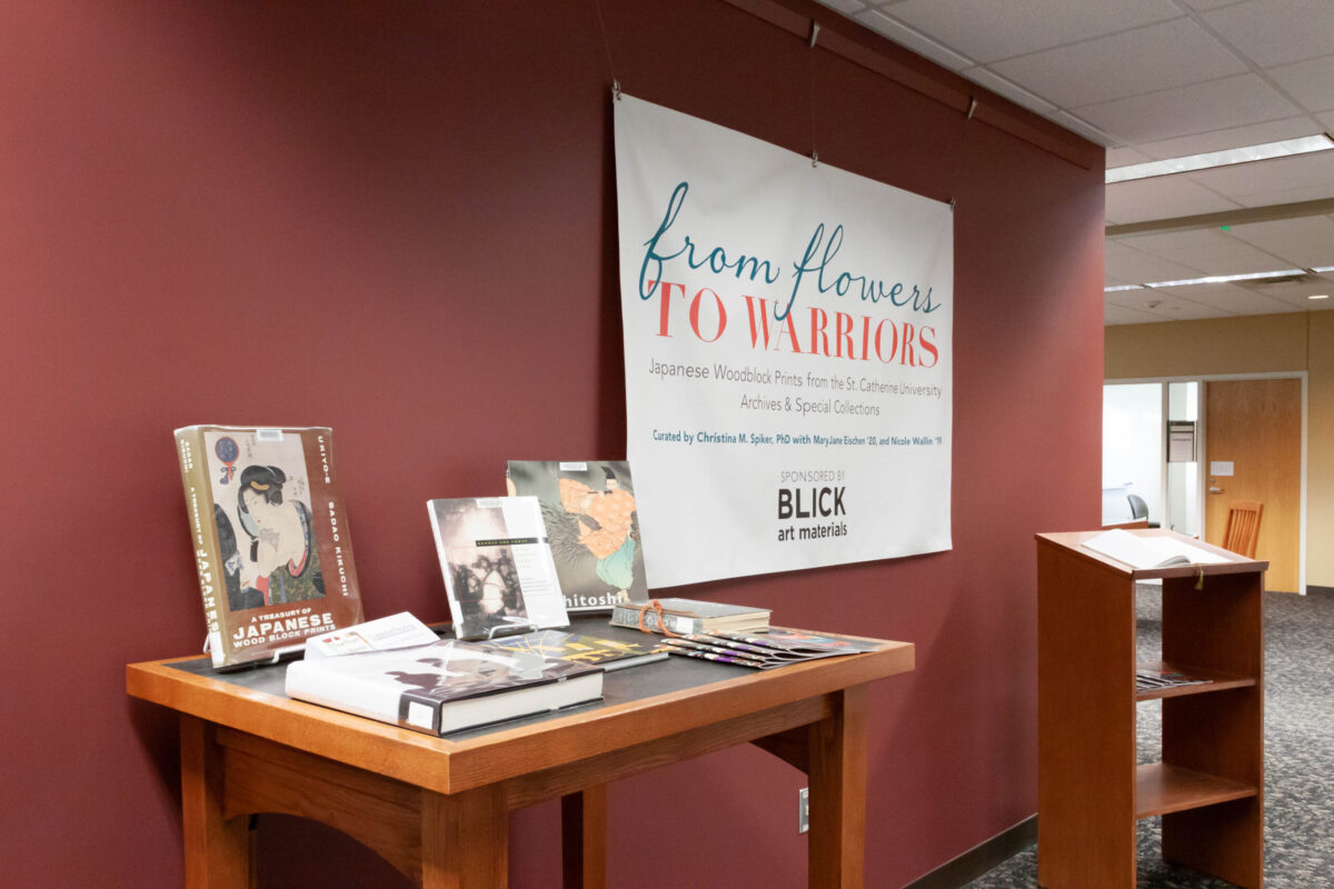 Installation view of From Flowers to Warriors in the St. Catherine University Library. Book display of related materials.